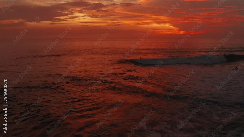 Flight Over Surfers Surfing Ocean Waves at Sunset. Amazing Sunset Aerial Ocean View. top down shot of textured ocean then reveals surfers in the sunset Flight Over Surfers Surfing Ocean Waves at Sunset. Amazing Sunset Aerial Ocean View. top down shot of textured ocean then reveals surfers in the sunset