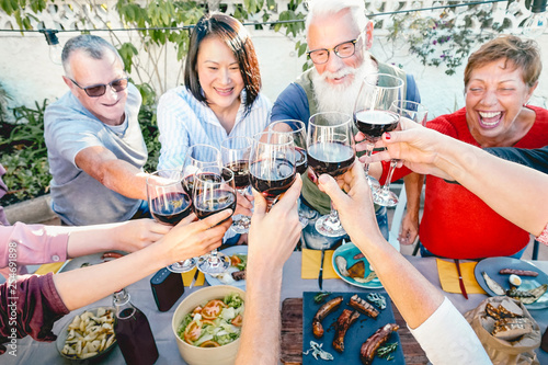 Photography Happy senior friends toasting with red wine glasses at dinner time outdoor - Mat
