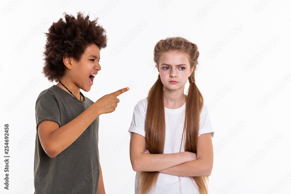 Angry long-haired girl resolutely crossing hands while boy pointing at ...