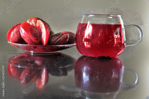 Plums in a saucer and a cup of juice on the table