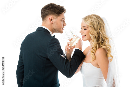 happy bride and groom drinking champagne isolated on white