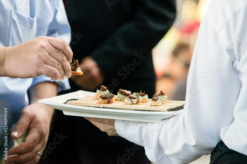 a server holding a tray full of snacks during a catered event