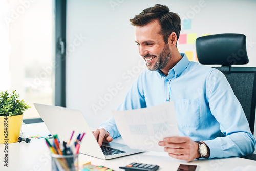 Happy businessman working with financail documents at office photo