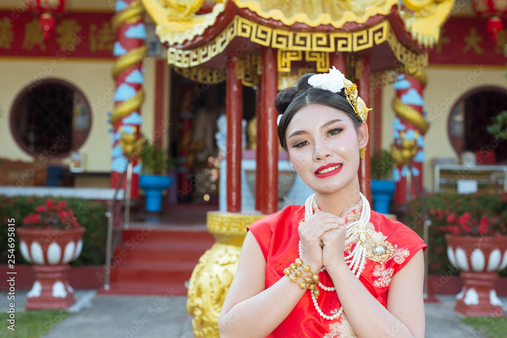 A beautiful Asian girl wearing a red worship g her gestures and smiling makes her look happy.