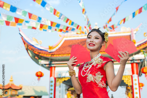 A beautiful asian girl wearing a red dress holding paper fan in her hand and smiling makes her look happy.