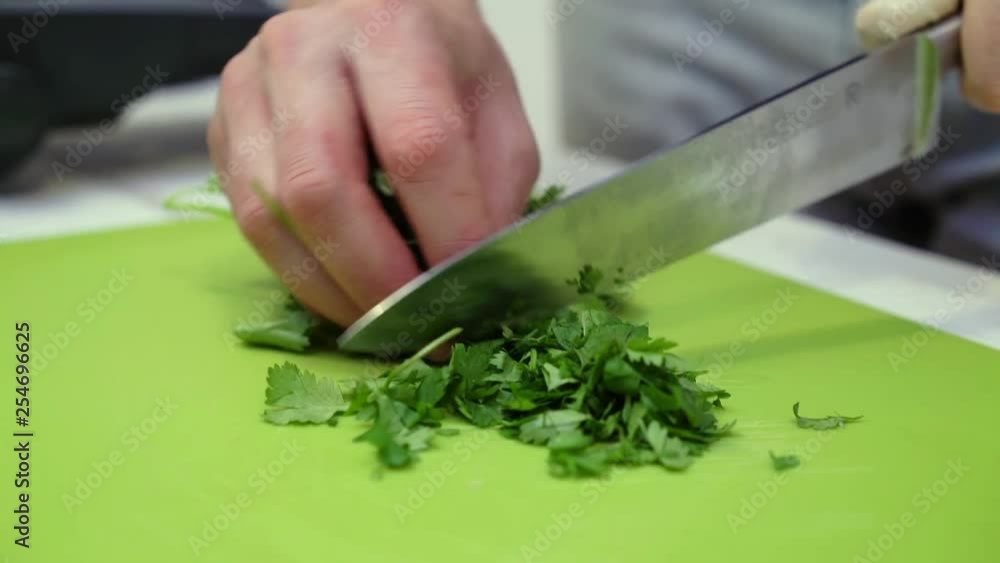 Close-up of Hands of a chef Cutting coriander on a green cutting board Close-up of Hands of a chef Cutting coriander on a green cutting board