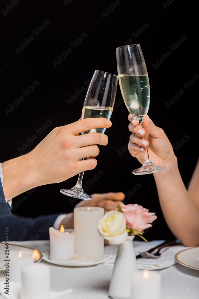 cropped view of man and woman holding glasses of champagne isolated on black cropped view of man and woman holding glasses of champagne isolated on black