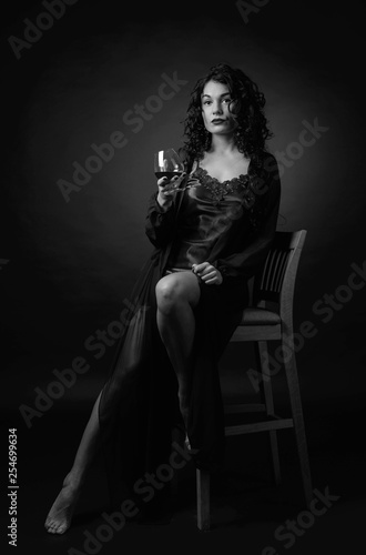 Portrait of attractive brunette with glass of brandy on a black background. © Igor Normann