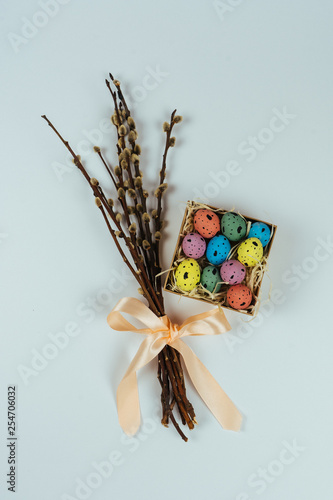 Colorful painted quail eggs in little box and willow branches isolated on white background. Easter holiday concept. Top view. Flat lay photo