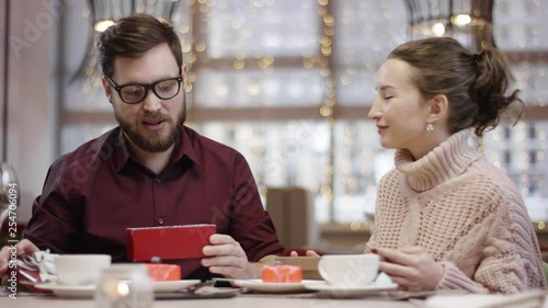 Adult man takes socks out of gift box his wife gave to him and seems unhappy