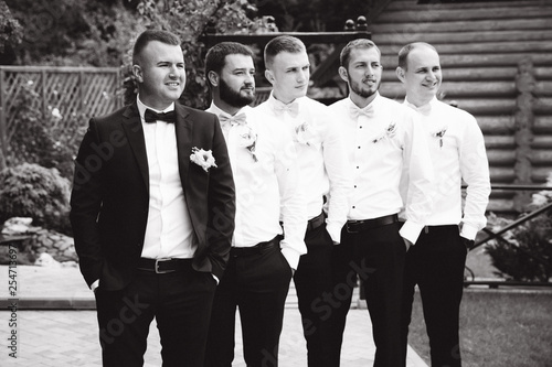 Stylish groomsman with groom standing on the backyard and prepare for the wedding ceremony. Friend spend time together outside