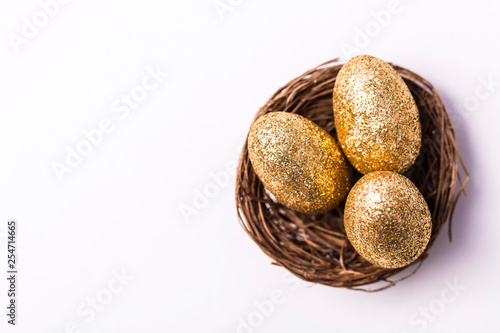 Golden glitter eggs in a nest. Easter background. Finance concept