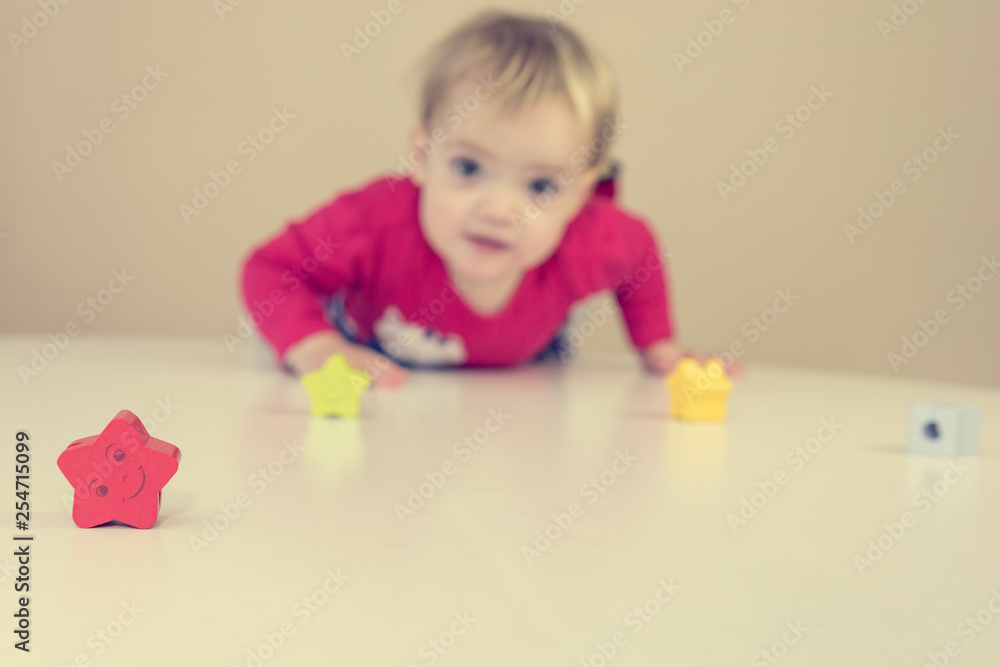 Cute blonde girl wearing red dress playing with toys at the table. Cute blonde girl wearing red dress playing with toys at the table.