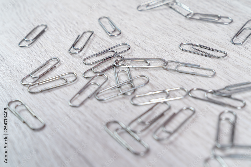Fototapeta premium Paper clips scattered on a gray wooden surface