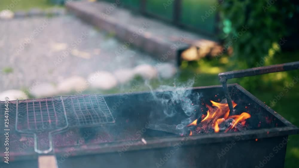 Close-up: man prepares the coals in the grill, stirs them with stick. Close-up: man prepares the coals in the grill, stirs them with stick.