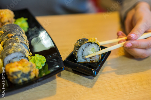 Girl takes sushi in the japanese restaurant