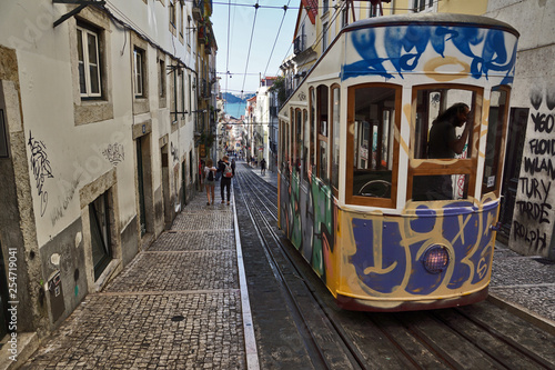 alte mit Graffiti bemalte Straßenbahn in Lissabon fährt Berg hoch, Portugal 