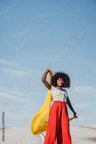 Afro woman with a yellow coloured scarf on the street © karrastock