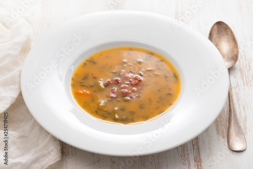 soup with smoked meat in white plate on wooden background