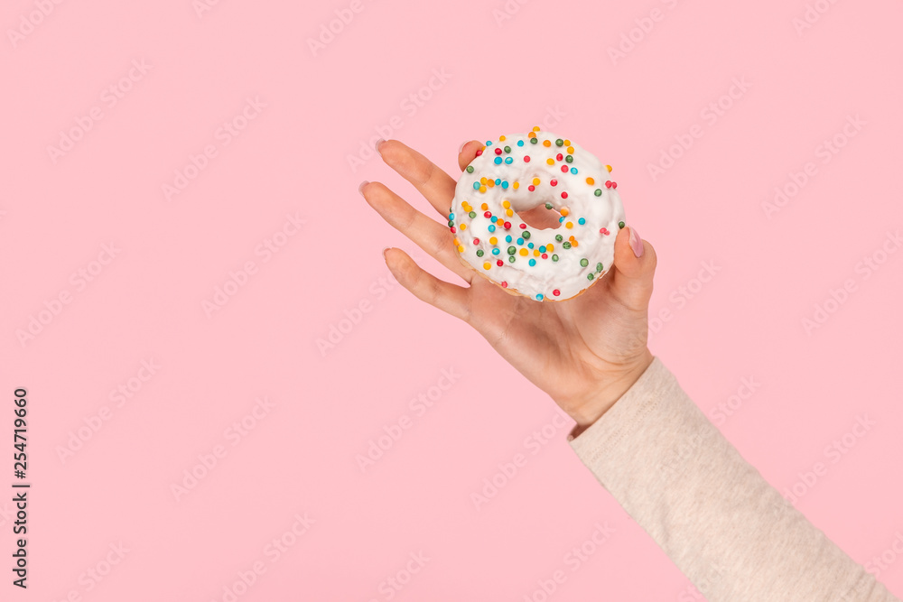 Crop hand demonstrating donut with sprinkles