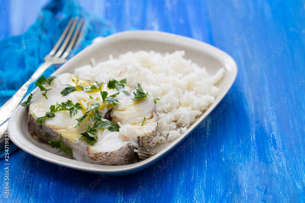 boiled perch with parsley and boiled rice on dish on blue wooden background boiled perch with parsley and boiled rice on dish on blue wooden background