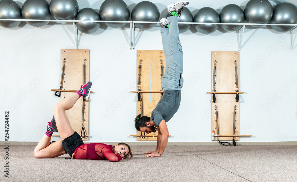 Young healthy yoga fitness acrobatic couple having fun in the gym performing  and practicing funny acrobat poses real people training workout Stock Photo