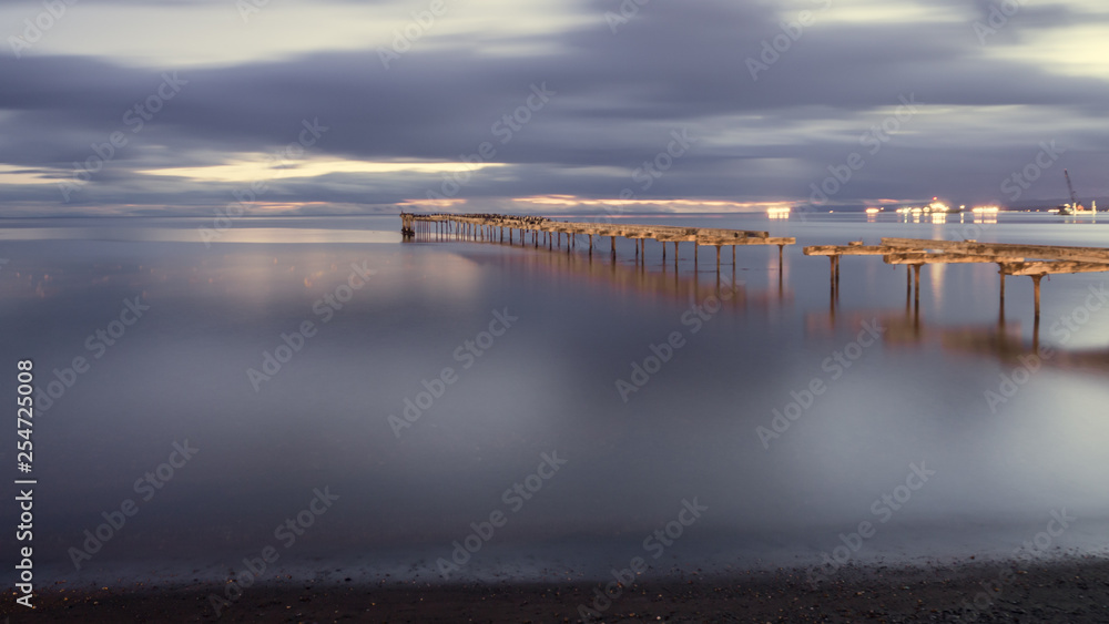 Old broken down wooden pier in Punta Arenas, old dock in Chile on the Pacific ocean. sunset