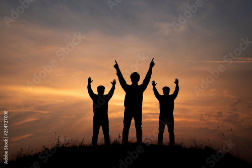 silhouette three men on peak mountain