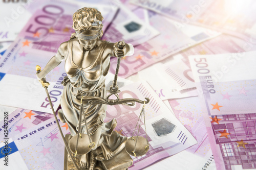 Eine goldene Justitia Figur steht auf vielen 500 Euro Geldscheinen. Konzeptionelles Bild zum Thema Gericht und Geld. Lens Flares. photo
