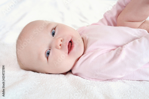 Portrait of a cute newborn baby lying on white bed sheet