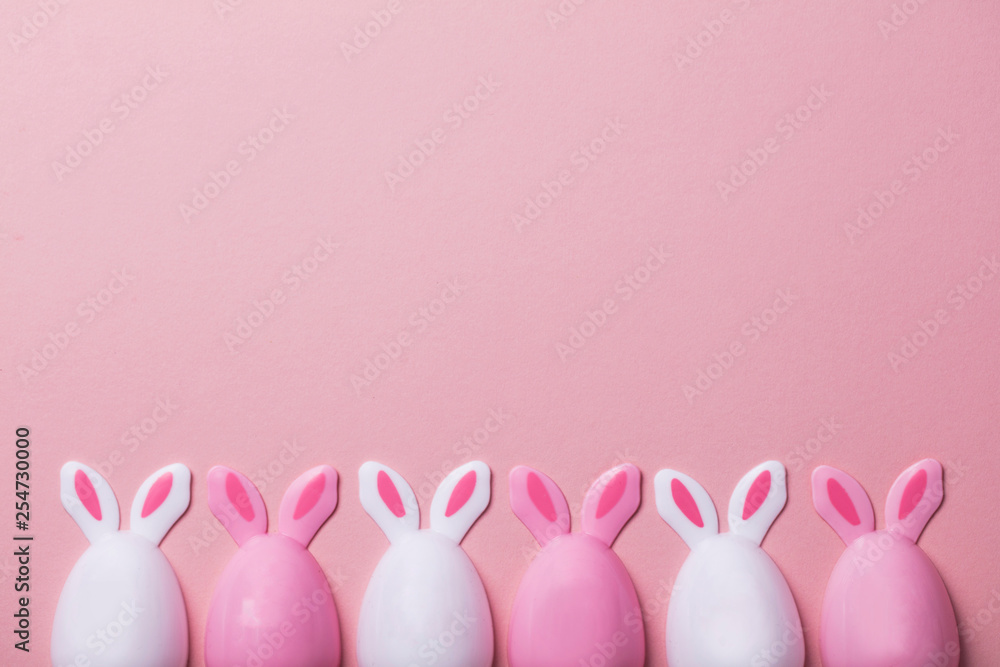 Easter eggs with bunny ears on a pastel pink background