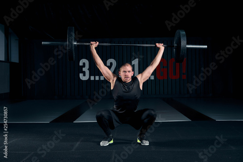 Young man with barbell flexing muscles and making shoulder press lunge in gym © nazarovsergey