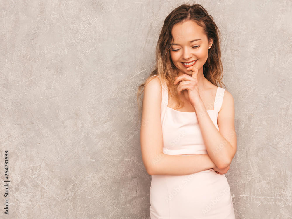 Portrait of young beautiful serious hipster girl in trendy summer light pink dress. Sexy carefree woman posing near gray wall. Positive model having fun Portrait of young beautiful serious hipster girl in trendy summer light pink dress. Sexy carefree woman posing near gray wall. Positive model having fun