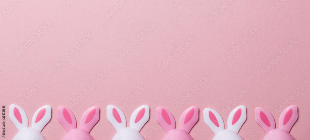 Fototapeta premium Easter eggs with bunny ears on a pastel pink background