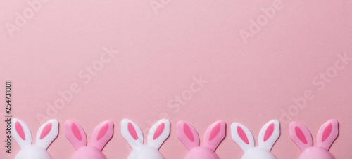 Easter eggs with bunny ears on a pastel pink background