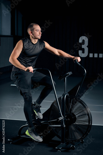 Fitness male using air bike for cardio workout at Functional training gym.