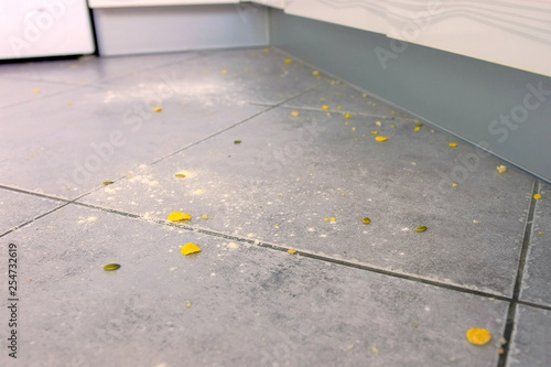 Dirty kitchen floor with food leftovers, flour, corn flakes after cooking. Close-up view. photo