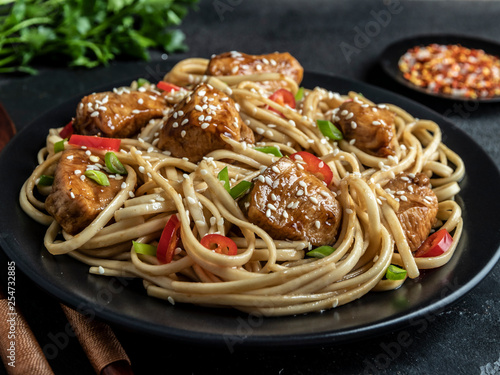 Asian noodles with chicken teriyaki   sesame  rustic stone background. Closeup. Chinese Japanese noodles