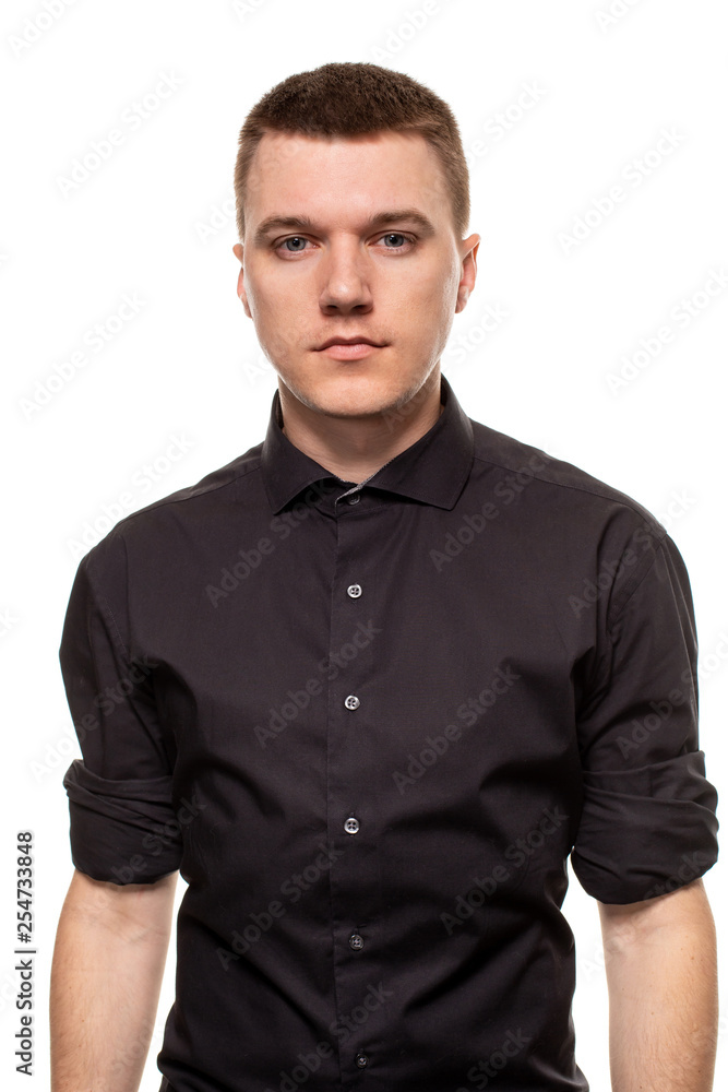 Handsome young man in a black shirt is making faces, while standing isolated on a white background Handsome young man in a black shirt is making faces, while standing isolated on a white background