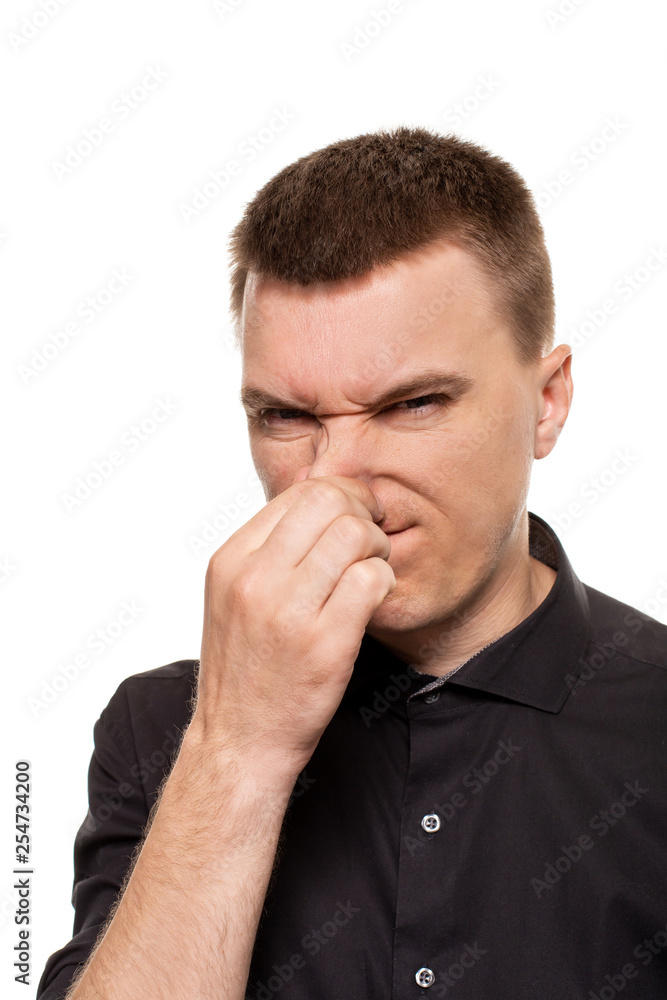 Handsome young man in a black shirt is making faces, while standing isolated on a white background Handsome young man in a black shirt is making faces, while standing isolated on a white background
