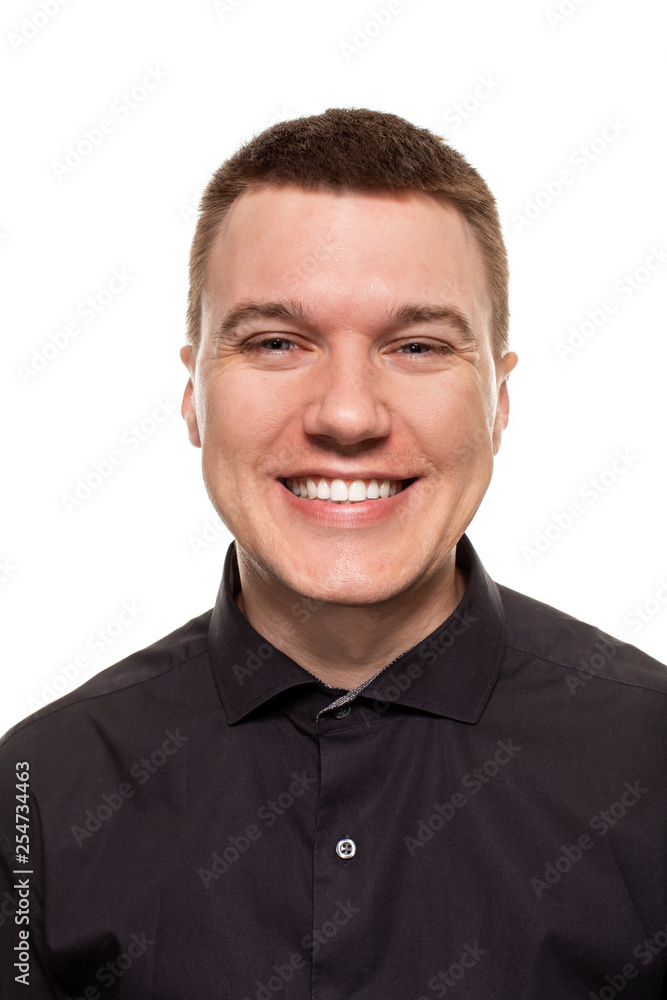 Handsome young man in a black shirt is making faces, while standing isolated on a white background Handsome young man in a black shirt is making faces, while standing isolated on a white background