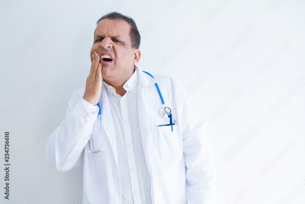 Middle age doctor man wearing stethoscope and medical coat over white background touching mouth with hand with painful expression because of toothache or dental illness on teeth. Dentist concept. Middle age doctor man wearing stethoscope and medical coat over white background touching mouth with hand with painful expression because of toothache or dental illness on teeth. Dentist concept.