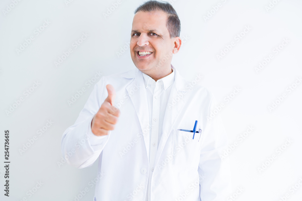 Middle age doctor man wearing medical coat over white background doing happy thumbs up gesture with hand. Approving expression looking at the camera with showing success. Middle age doctor man wearing medical coat over white background doing happy thumbs up gesture with hand. Approving expression looking at the camera with showing success.