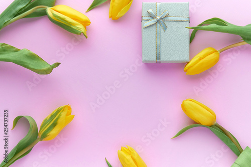 Yellow tulips and gift boxes on a pink background with copy space © Александр Гаврилычев
