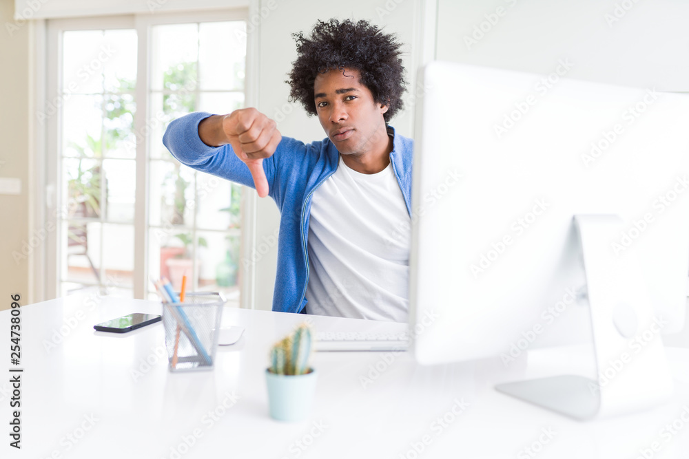 African American man working using computer with angry face, negative sign showing dislike with thumbs down, rejection concept