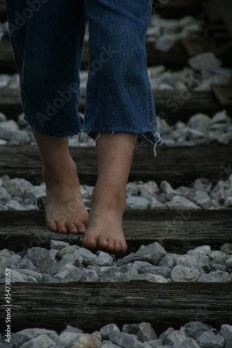 Young boy walks barefoot on abandoned railroad tracks © Stephen