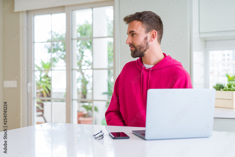 Handsome man working using computer laptop looking to side, relax profile pose with natural face with confident smile. Handsome man working using computer laptop looking to side, relax profile pose with natural face with confident smile.