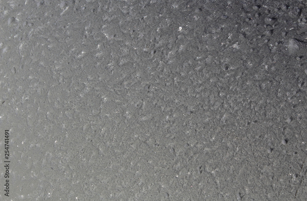Frost in winter formed on a gray smooth surface
