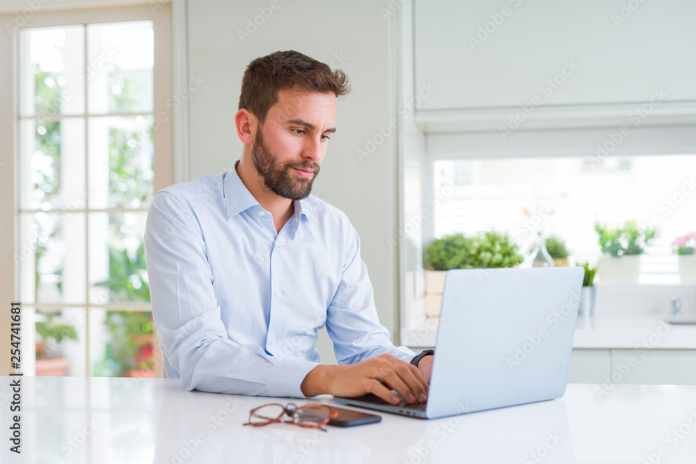 Handsome business man working using computer laptop with a confident expression on smart face thinking serious