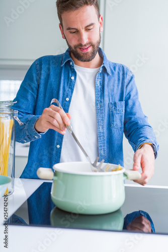 Handsome man cooking pasta at home